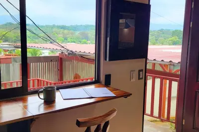 a desk in a room with a view of a balcony at Local secret apartament Blue Mountain in Quepos in Quepos