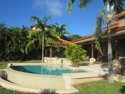 a swimming pool in front of a house with palm trees at Casa Paulina in Playa Conchal