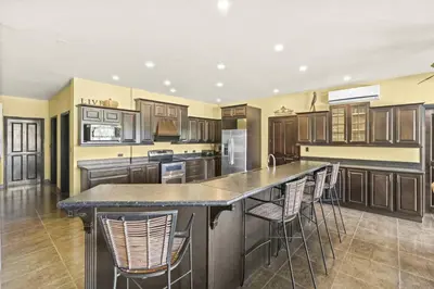 a kitchen with wooden cabinets and a island with bar stools at Casa Paulina in Playa Conchal