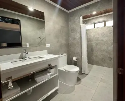 a bathroom with a toilet and a sink and a mirror at Casa Marigold in Coyol