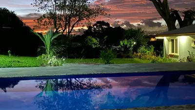 a house with a pool in front of a sunset at Casa Marigold in Coyol