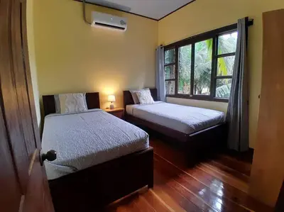 a bedroom with two beds and a window at Riverside Oasis Cabin with A C in Guápiles