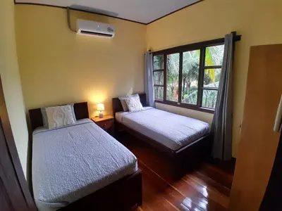 a small room with two beds and a window at Riverside Oasis Cabin with A C in Guápiles