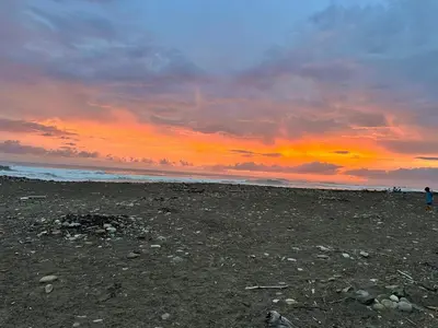 a sunset on a beach with people walking on the beach at Cabinas Paraíso in Dominical