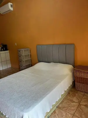 a bed in a bedroom with an orange wall at Cabinas Paraíso in Dominical