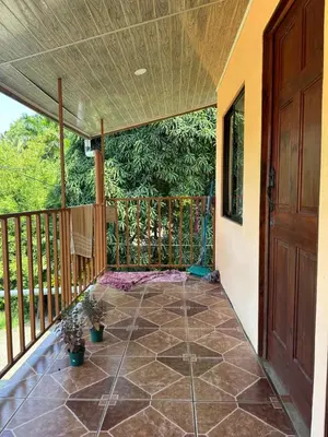 a screened porch with a wooden door and plants at Cabinas Paraíso in Dominical