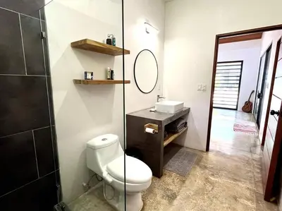 a bathroom with a toilet and a sink and a mirror at 3 Bdr Villa With Pool , Near beach, Fast Wifi in Veintisiete de Abril
