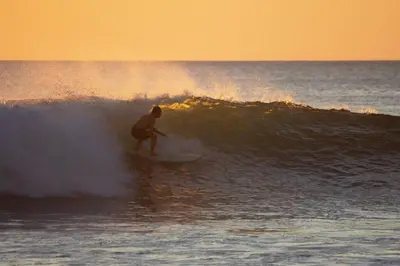 a man riding a wave on a surfboard in the ocean at 3 Bdr Villa With Pool , Near beach, Fast Wifi in Veintisiete de Abril