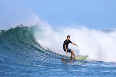 a man riding a wave on a surfboard in the ocean at 3 Bdr Villa With Pool , Near beach, Fast Wifi in Veintisiete de Abril