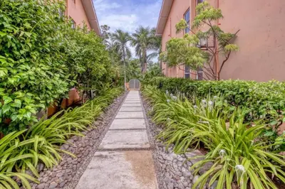 a garden path between two buildings with plants at BLA1 3 Bedroom Condo with Direct Beach Access in Tamarindo