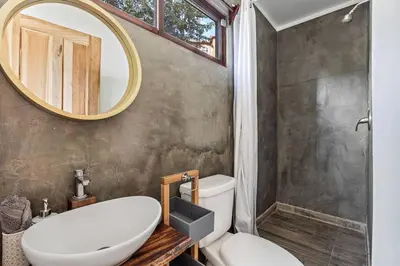 a bathroom with a white toilet and a mirror at Casa Indy 3bdrm Home with Pool in Town Centre in Tamarindo