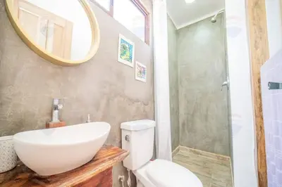 a bathroom with a sink and a toilet and a mirror at Casa Indy 3bdrm Home with Pool in Town Centre in Tamarindo