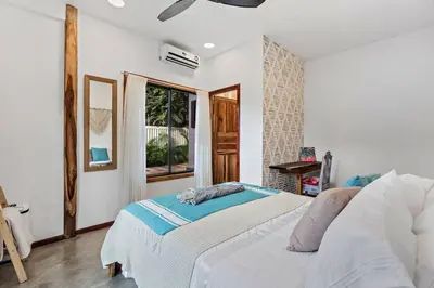 a white bedroom with a bed and a window at Casa Indy 3bdrm Home with Pool in Town Centre in Tamarindo