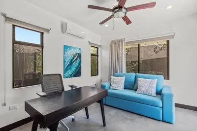 a living room with a blue couch and a ceiling fan at CU15 New Modern Home with Casitas and Private Pool in Tamarindo