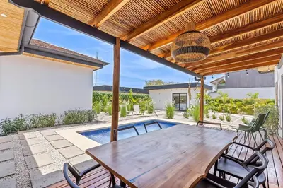 a patio with a wooden table and chairs under a pergola at CU19 New 3 Bdrm Mod Home with Casita Prv Pool in Villarreal