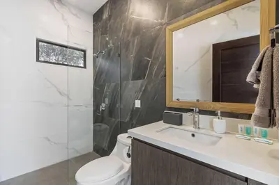 a bathroom with a toilet and a sink and a mirror at CU20 Modern Beach Home w Guest House & Pvt Pool in Villarreal