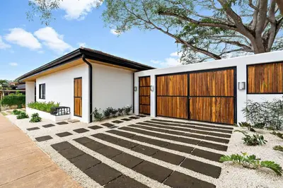 a white house with a wooden garage door at CU27 New Construction 3bdrm Home with Prv Pool in Tamarindo