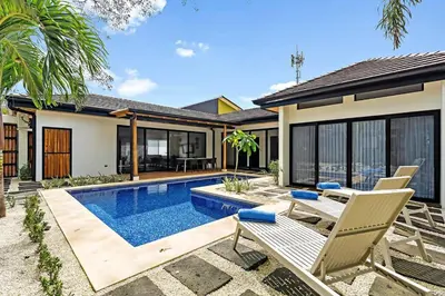 a house with a swimming pool and two chairs at CU27 New Construction 3bdrm Home with Prv Pool in Tamarindo