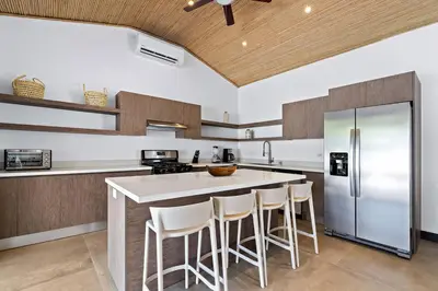 a kitchen with a large island with bar stools at CU27 New Construction 3bdrm Home with Prv Pool in Tamarindo