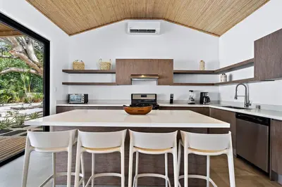 a kitchen with a large island with white counter chairs at CU27 New Construction 3bdrm Home with Prv Pool in Tamarindo