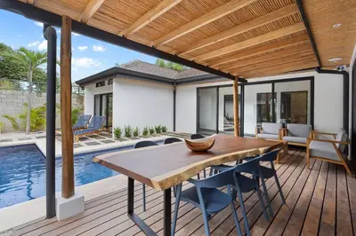 a wooden deck with a table and chairs and a swimming pool at CU7 Beach Home Oasis with Private Pool and Guest House in Barco Quebrado