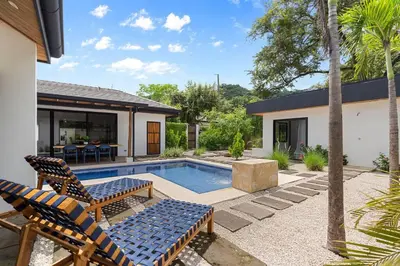 a backyard with a pool and two chairs and a house at CU7 Beach Home Oasis with Private Pool and Guest House in Barco Quebrado