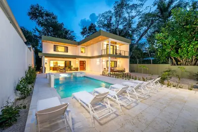 a house with a swimming pool and white chairs at Modern New Villa in Playa Potrero Close to Beach in Potrero