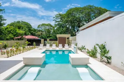 a swimming pool with lounge chairs next to a building at Modern New Villa in Playa Potrero Close to Beach in Potrero