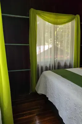 a bedroom with a green curtain and a window at Aventura Familiar Bosque Tropical Volcán Arenal in San Ramón