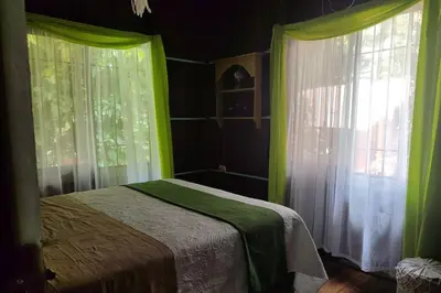 a bedroom with green and white curtains and a bed at Aventura Familiar Bosque Tropical Volcán Arenal in San Ramón