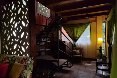 a living room with a spiral staircase and a couch at Aventura Familiar Bosque Tropical Volcán Arenal in San Ramón