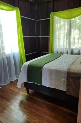 a bedroom with a bed with green curtains at Aventura Familiar Bosque Tropical Volcán Arenal in San Ramón
