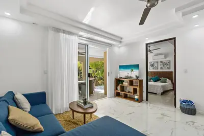 a living room with a blue couch and a mirror at Gav10 Modern Pool Side Condo in Quiet Area of Tam in Tamarindo