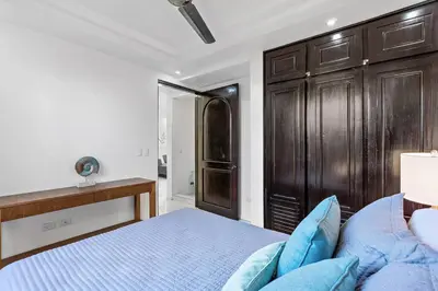 a bedroom with a bed and a wooden cabinet at Gav10 Modern Pool Side Condo in Quiet Area of Tam in Tamarindo