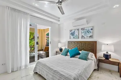 a white bedroom with a bed with blue pillows at Gav10 Modern Pool Side Condo in Quiet Area of Tam in Tamarindo