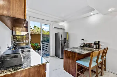 a kitchen with a counter with a sink and a refrigerator at Gav10 Modern Pool Side Condo in Quiet Area of Tam in Tamarindo