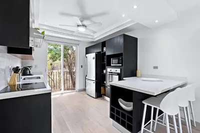 a kitchen with black cabinets and a white refrigerator at Gav5 New Modern Condo Walking Distance to Beach in Tamarindo