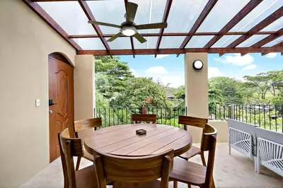 a dining room with a wooden table and a ceiling fan at Gav5 New Modern Condo Walking Distance to Beach in Tamarindo