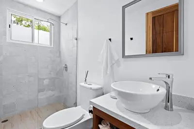 a bathroom with a sink and a toilet and a mirror at Gav5 New Modern Condo Walking Distance to Beach in Tamarindo