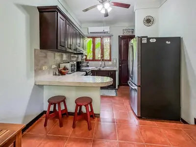 a kitchen with a black refrigerator and two stools at LSI1 Cozy 2 Bdrm Villa Central and Steps to Beach in Tamarindo
