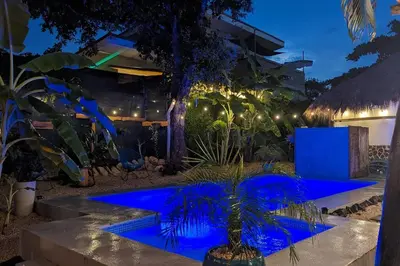 a garden with a blue pool at night at Matambú Rancho Rustic 2bd Apt with Shared Pool in Matapalo