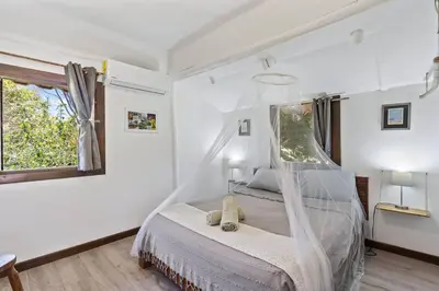 a bedroom with a bed with a mosquito net at Matambú Rancho Rustic 2bd Apt with Shared Pool in Matapalo