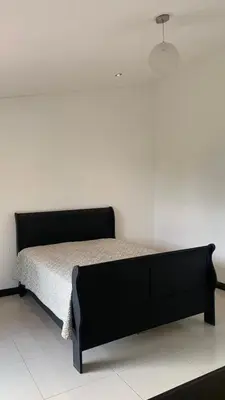 a bed in a room with a white wall at sarahs peaceful Home in Parrita