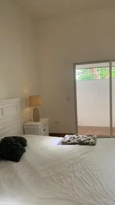 a bedroom with a white bed with a lamp and a window at sarahs peaceful Home in Parrita