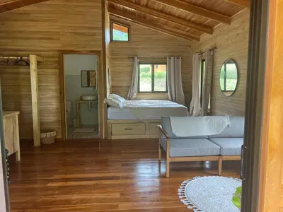 a bedroom with a bed and a couch and a window at Almond Suite - Blue Zone Costa Rica, Hojancha in Caimital