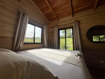 a bed in a room with a large window at Almond Suite - Blue Zone Costa Rica, Hojancha in Caimital