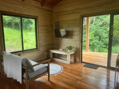a living room with a chair and a tv and windows at Almond Suite - Blue Zone Costa Rica, Hojancha in Caimital