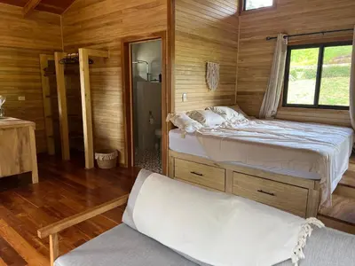 a bedroom with two beds in a wooden cabin at Almond Suite - Blue Zone Costa Rica, Hojancha in Caimital