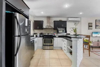 a kitchen with a stainless steel refrigerator and white cabinets at Nax3 Luxury Condo in Upscale Langosta Community in Tamarindo