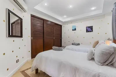 two beds in a bedroom with white walls at Nax3 Luxury Condo in Upscale Langosta Community in Tamarindo